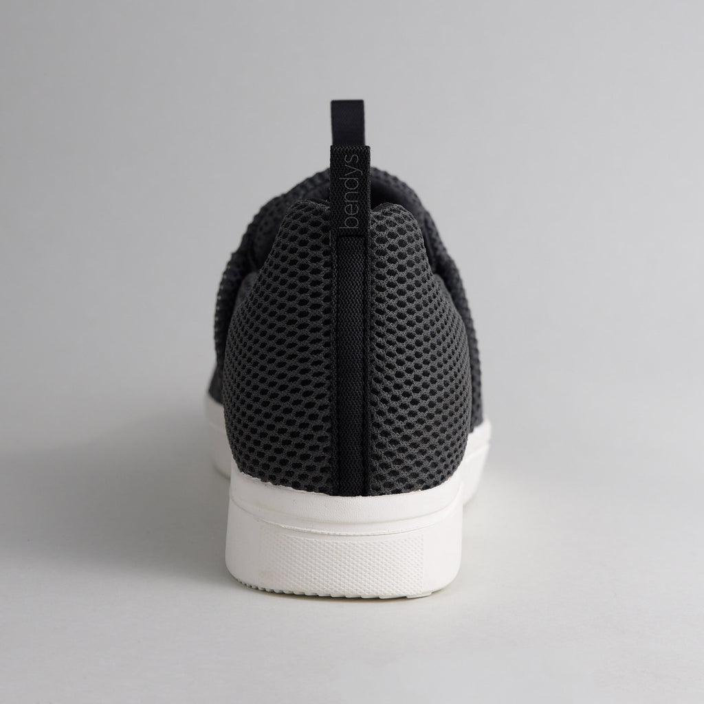 Rückansicht eines schwarzen bendys Sneakers: Fokus auf die Fersenlasche mit Marken-Branding und das atmungsaktive Mesh-Gewebe über der stabilen weißen Sohle.