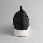 Rückansicht eines schwarzen bendys Sneakers: Fokus auf die Fersenlasche mit Marken-Branding und das atmungsaktive Mesh-Gewebe über der stabilen weißen Sohle.