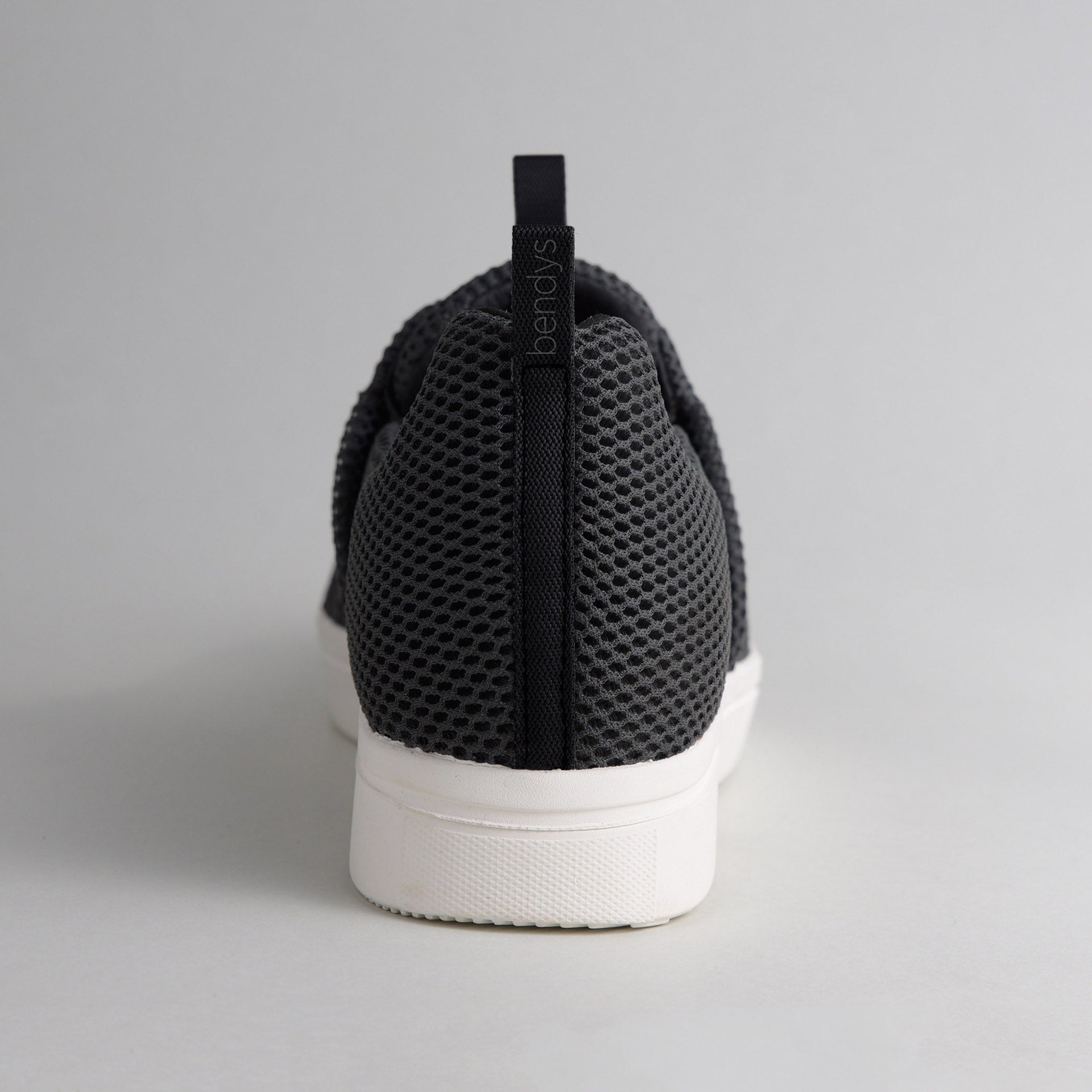 Rückansicht eines schwarzen bendys Sneakers: Fokus auf die Fersenlasche mit Marken-Branding und das atmungsaktive Mesh-Gewebe über der stabilen weißen Sohle.