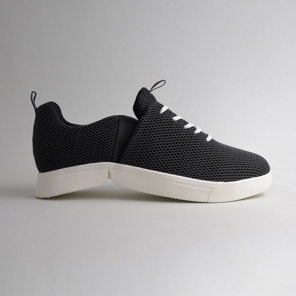 Seitenansicht des schwarzen bendys Mesh-Sneakers im halbgeöffneten Zustand: Deutliche Darstellung der zweigeteilten, weißen Klappsohle, die den händefreien Einstieg ermöglicht