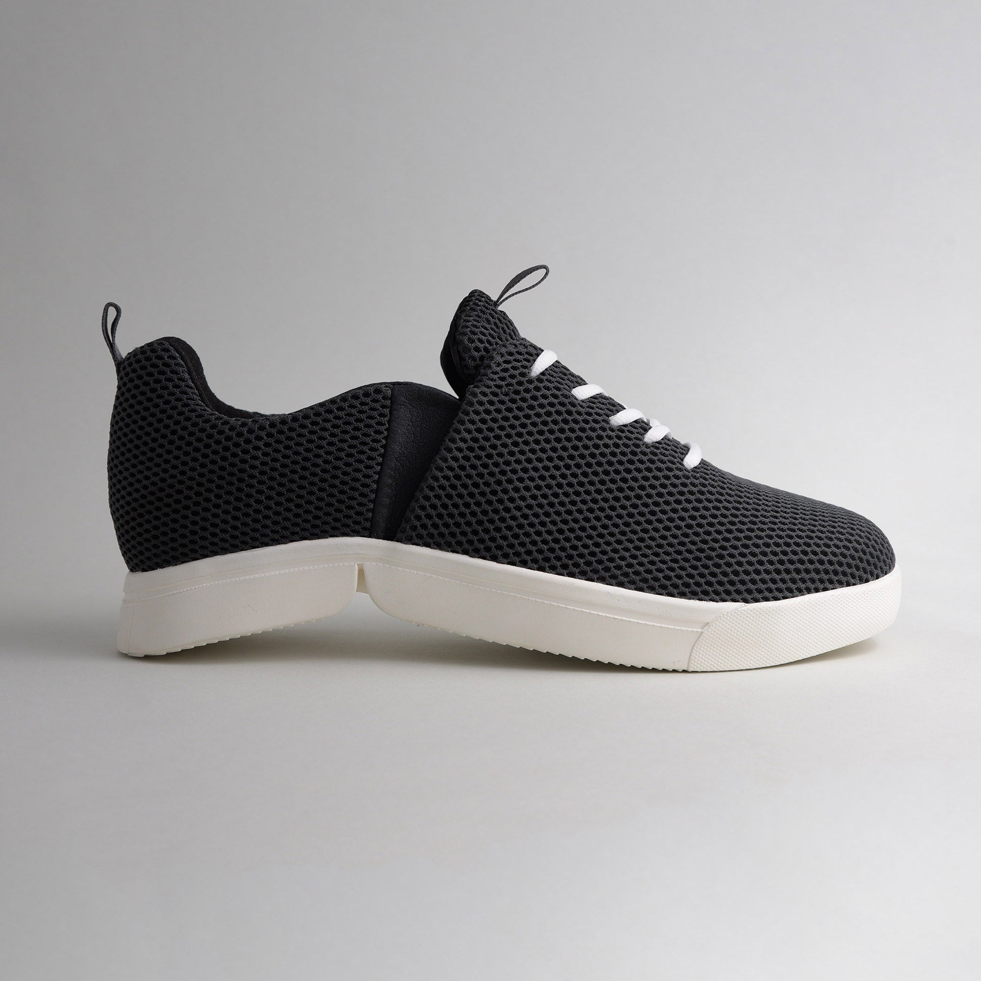 Seitenansicht des schwarzen bendys Mesh-Sneakers im halbgeöffneten Zustand: Deutliche Darstellung der zweigeteilten, weißen Klappsohle, die den händefreien Einstieg ermöglicht
